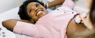 Happy smiling pregnant African American woman getting ultrasound from doctor at her prenatal appointment.