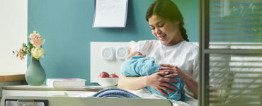 young woman sitting in hospital bed holding and breastfeeding newborn baby