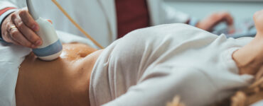 A female patient laying down while having an ultrasound on her abdomen.