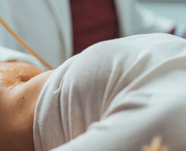 A female patient laying down while having an ultrasound on her abdomen.