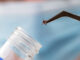 A researcher wearing gloves in a lab holding a tick with a tweaser.