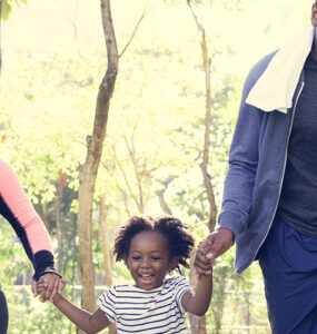 Parents and young daughters exercising outside together.
