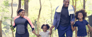 Parents and young daughters exercising outside together.