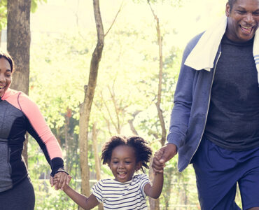 Parents and young daughters exercising outside together.