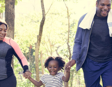 Parents and young daughters exercising outside together.