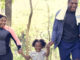 Parents and young daughters exercising outside together.