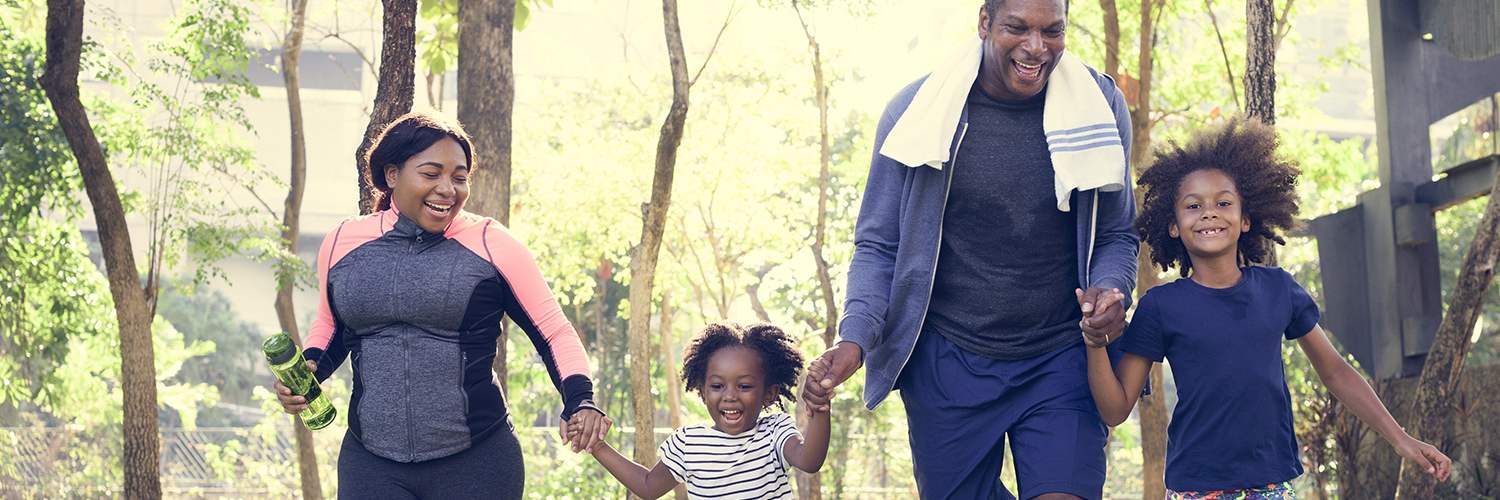 Parents and young daughters exercising outside together.