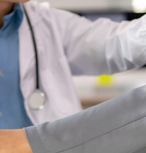 A doctor is helping a patient with a foot injury. The patient is wearing a gray and white outfit.