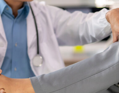 A doctor is helping a patient with a foot injury. The patient is wearing a gray and white outfit.