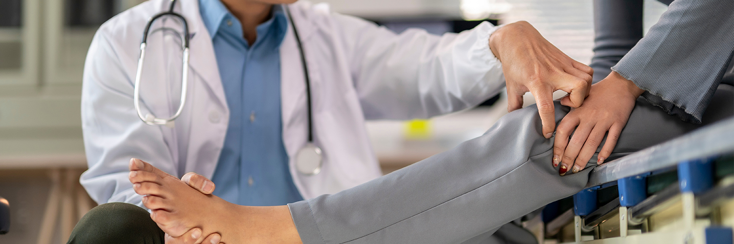 A doctor is helping a patient with a foot injury. The patient is wearing a gray and white outfit.