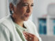 Senior, sick woman heartburn with symptoms for discomfort, acid reflux or viral gastro disease at hospital.