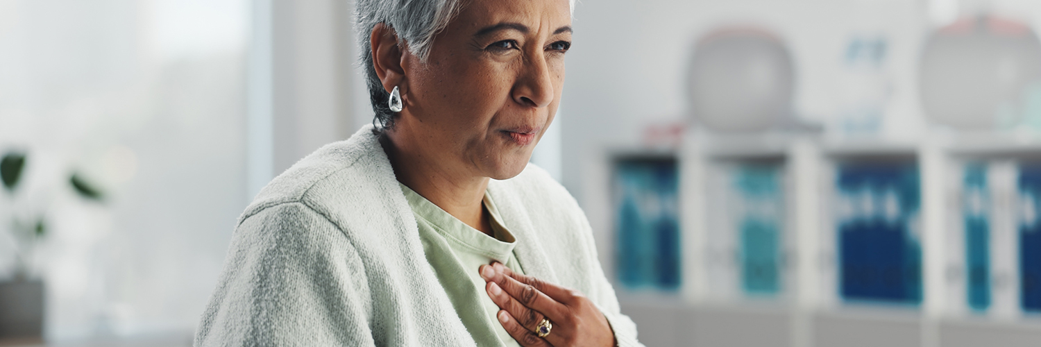 Senior, sick woman heartburn with symptoms for discomfort, acid reflux or viral gastro disease at hospital.