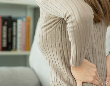 woman holding her lower back while suffering from unbearable back pain from a herniated disc.