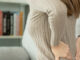 woman holding her lower back while suffering from unbearable back pain from a herniated disc.