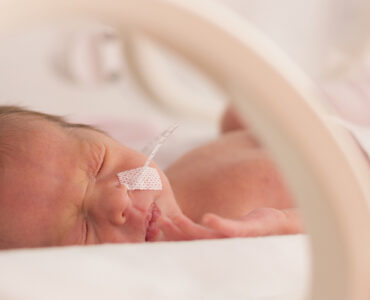Premature newborn baby girl in the hospital incubator.
