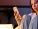 Teenage girl sitting at a desk in her bedroom at night looking at a mobile phone, illustrating teen screen time.