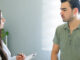 A young man speaking to a female physician inside a medical office.