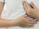Woman with burning in the chest suffering from indigestive problem.