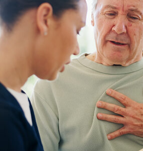 Senior man with chest pain talking to nurse.