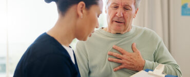 Senior man with chest pain talking to nurse.