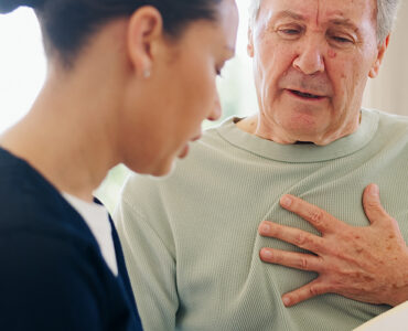 Senior man with chest pain talking to nurse.