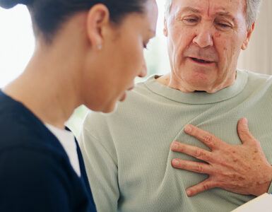 Senior man with chest pain talking to nurse.