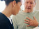Senior man with chest pain talking to nurse.
