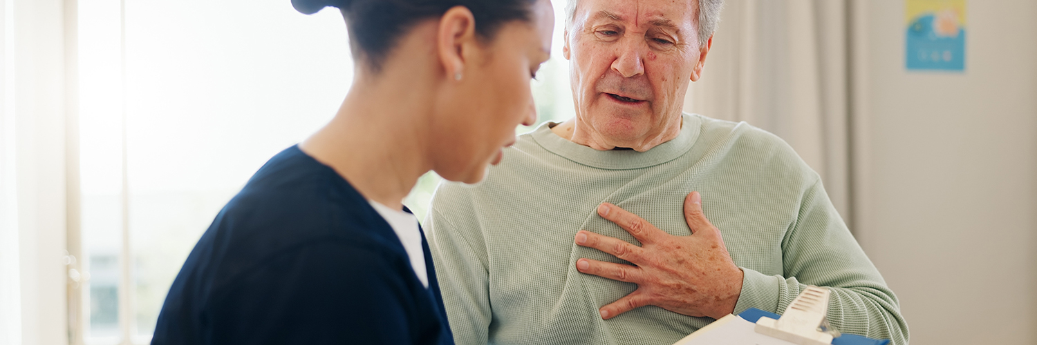 Senior man with chest pain talking to nurse.